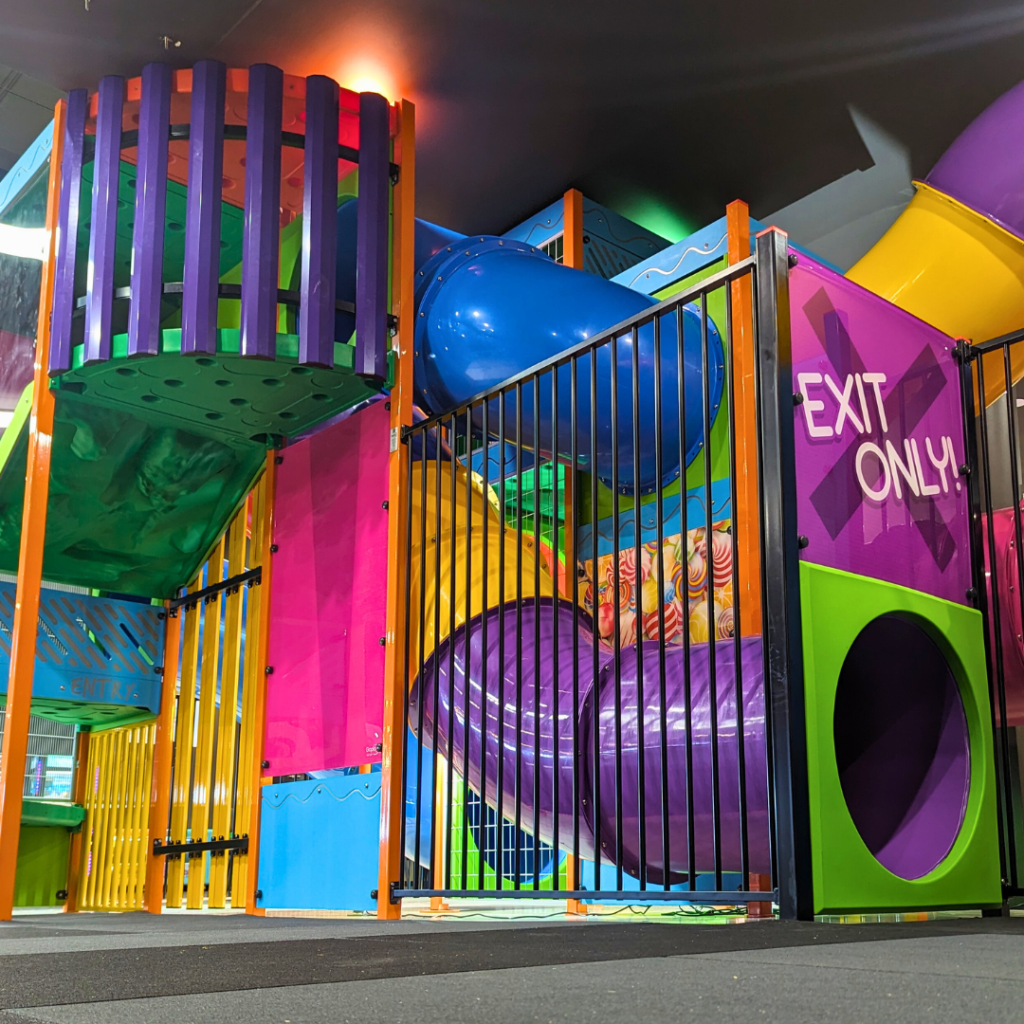 Colourful indoor kids playground, with tube slides and climbing steps. With a caption "bring the kids."